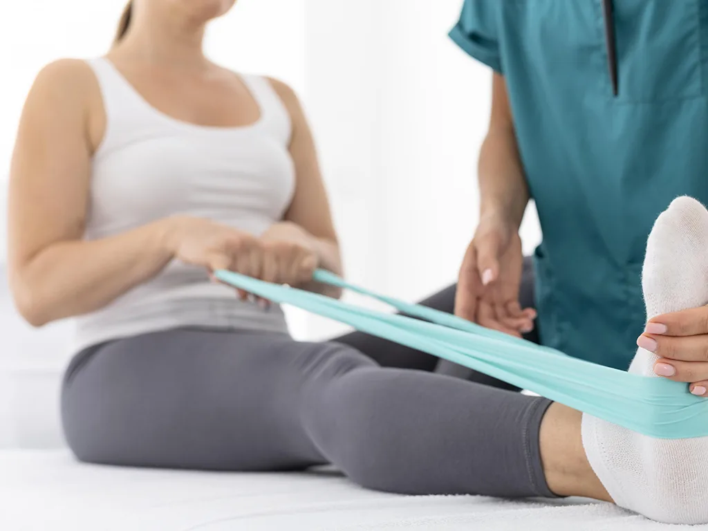 Seduta di fisioterapia: esercizio con elastico seguito dal fisioterapista